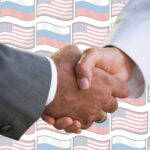 Image of a handshake with a background pattern of the US and Russian flags